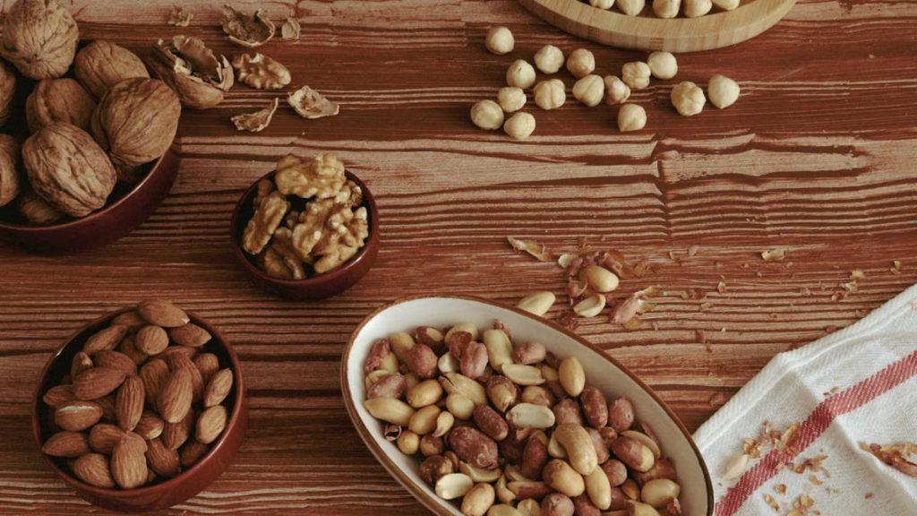 A variety of nuts including almonds, walnuts, and peanuts on a rustic table.
