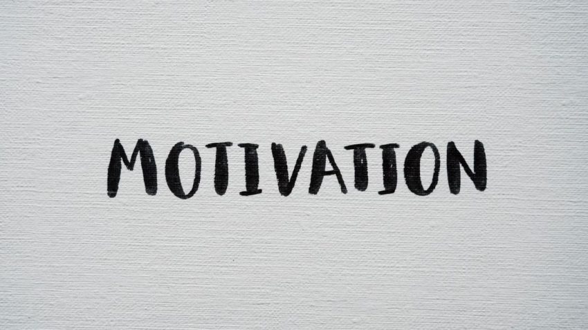Inspirational word 'Motivation' in black on a white textured canvas background.
